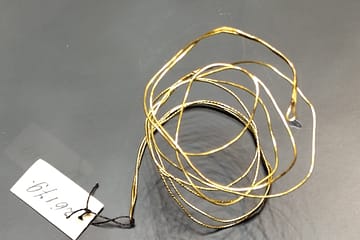Gold threads - a coil of gold thread with a label